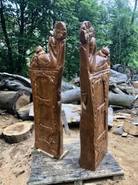 two wood carvings on top of a pile of wood