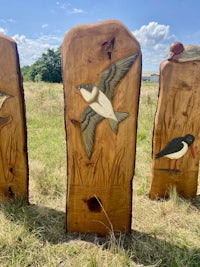 three wooden carvings of birds in a field