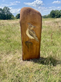 a wooden carving of a bird in a field