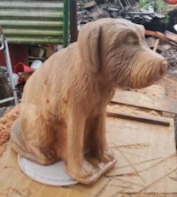 a wooden sculpture of a dog sitting on top of a piece of wood