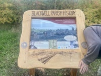 a man leaning over a wooden sign that says blackwell parish history