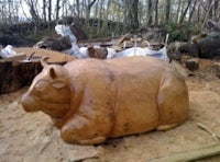 a large wooden sculpture of a cow in the woods