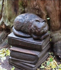 a statue of a cat resting on a stack of books