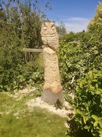 an owl carving on a tree stump in a garden