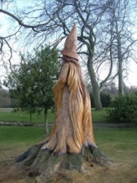 a wooden statue of a witch on top of a tree stump