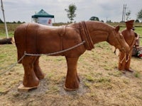 a wooden sculpture of a horse and a man standing next to it