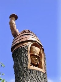 a tree trunk with a carving of a man in a hat