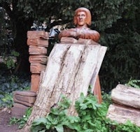 a statue of a man sitting next to a pile of logs