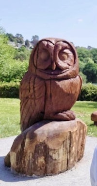 an owl sculpture on a log in a park