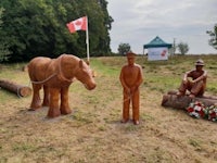 two wooden statues of a man and a horse in a field